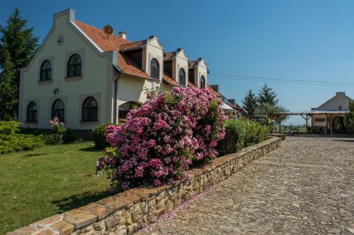 毛科Garden Vendégház Makó的石墙前有粉红色花的房屋