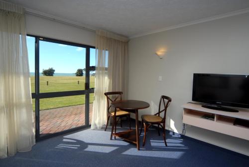 纳皮尔Harbour View Seaside Accommodation Napier的客厅配有桌椅和电视。