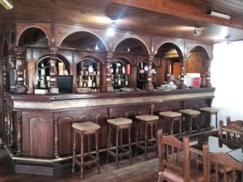 MacachínHotel y Restaurant Don Quijote的餐厅里的酒吧,有凳子和酒瓶