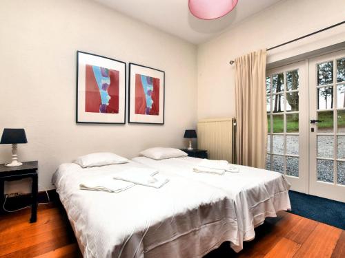 埃尔泽Luxury holiday home in Érezée的卧室设有一张白色大床和两个窗户。
