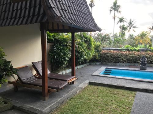 乌布巴厘岛微风别墅酒店的游泳池旁的遮阳伞和椅子