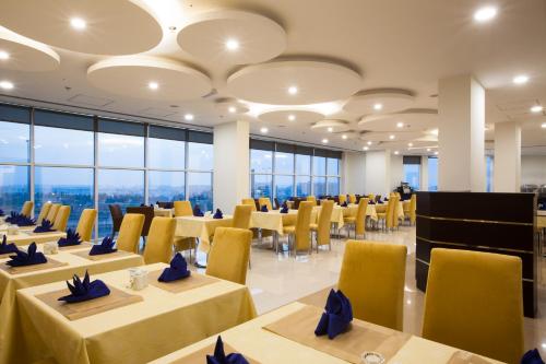 马斯喀特阿马拉酒店的用餐室设有桌子和黄色的椅子以及窗户。
