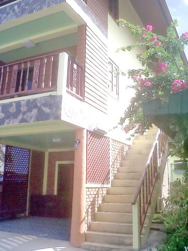 邦涛海滩Village Apartment Phan 123的一座带楼梯的建筑,通往一座拥有粉红色花卉的建筑