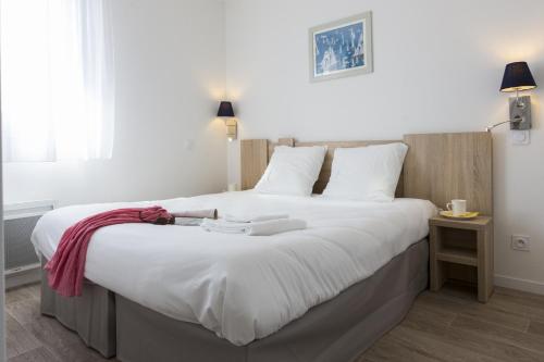 诺亚芒提亚Résidence Prestige Odalys Le Domaine des Pins的一间卧室配有一张带白色床单的大床