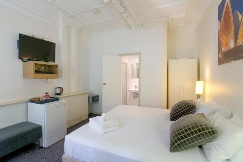 悉尼中立湾旅馆的一间酒店客房,配有白色的床和电视