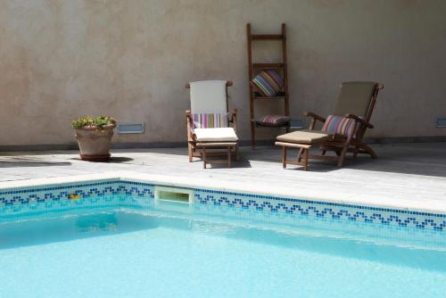 波格尔la Palisse的一个带两把椅子和一张桌子的游泳池