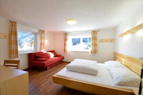 伊施格尔Apart Muntane的一间卧室配有一张床和一张红色的沙发