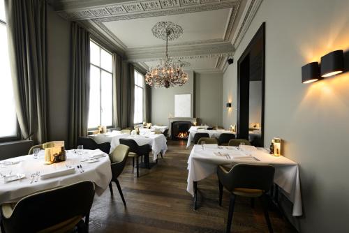 科特赖克梅塞恩酒店的餐厅配有白色的桌椅和吊灯