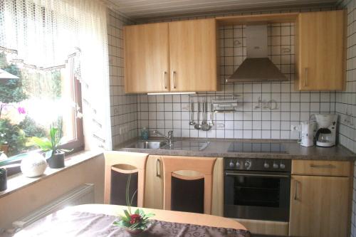 施莱登Ferienwohnung-Geschwind的厨房配有木制橱柜、水槽和炉灶。