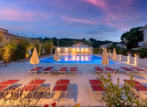 努马纳Hotel Giardino Suites&Spa的一个带桌椅和遮阳伞的游泳池