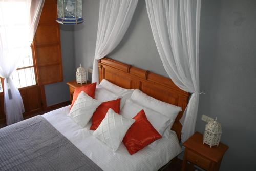 隆达La Casita Gris的一间卧室配有红色和白色枕头的床