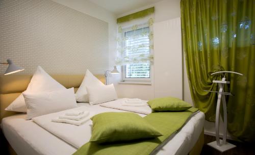 柏林Am Schmeding的白色的床、绿色和白色枕头以及窗户