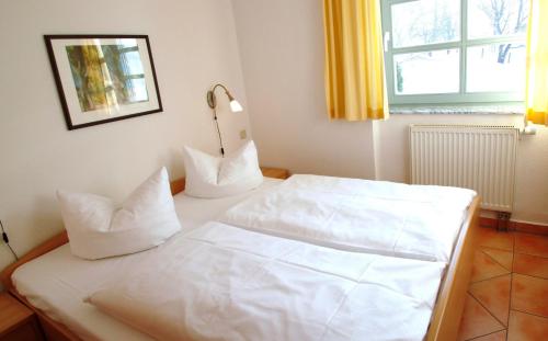 奥斯特巴德·哥伦Ferienhaus-mit-Schwimmbad-Sauna的一张带白色床单和枕头的床