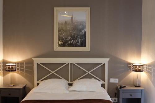 里摩日Hôtel Bistrot Le Marceau的一间卧室配有一张带2个床头柜和2盏灯的床。