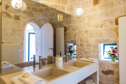 奇斯泰尼诺Borgo Canonica的一间带两个水槽和石墙的浴室