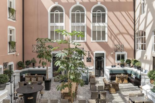 延雪平克莱里昂珍藏维多利亚酒店的粉红色建筑的庭院,有桌子和植物
