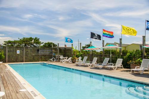 纳格斯黑德First Colony Inn的游泳池配有椅子、遮阳伞和旗帜