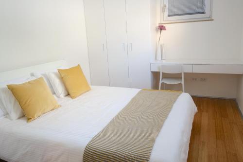 卢布尔雅那Sensei apartment的客房内的白色床和两个黄色枕头