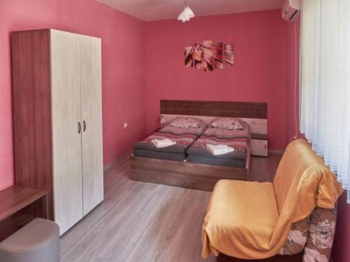 索非亚АПАРТАМЕНТ ЗА ГОСТИ "Момчил''的卧室设有粉红色的墙壁、一张床和椅子