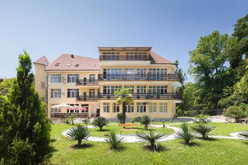 霍斯塔Hotel Staraya Khosta的一座黄色的大建筑,有树庭院