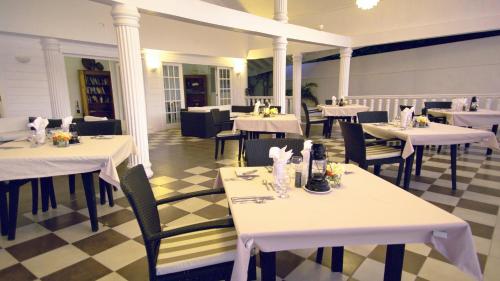 Union Island大卫海滩酒店的餐厅设有白色的桌椅和 ⁇ 格地板