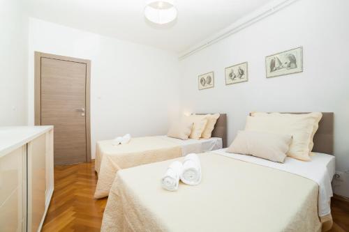 扎达尔Casa Ana的配有白色墙壁和木地板的客房内的两张床