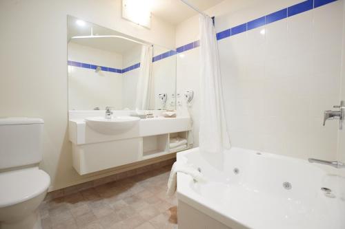 汉密尔顿汉密尔顿文图拉套房酒店的一间带水槽、浴缸和卫生间的浴室