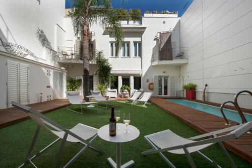 桑卢卡尔-德巴拉梅达La Alcoba del Agua hotel boutique的庭院配有椅子和一张桌子及一瓶葡萄酒