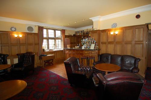 惠特比邓斯利庄园乡村别墅酒店的一间设有皮椅和桌子的房间和一间酒吧