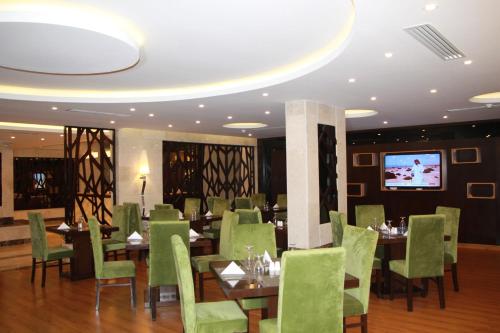 阿尔卡夫奇AlMuhaidb Residence Alkhafji的餐厅设有绿色的桌椅和电视。