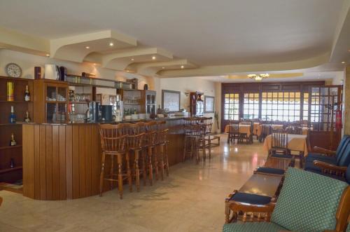 普托莱迈达Hotel Costis的餐厅设有酒吧,配有一些桌椅