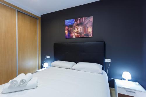 阿利坎特圣巴巴拉公寓酒店的卧室配有白色的床,墙上配有电视