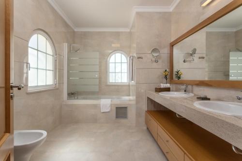阿尔沃尔Villa Amarela的一间带两个盥洗盆、浴缸和卫生间的浴室