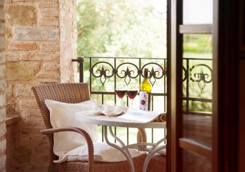 阿西西德波卡圣克里斯皮诺住宅酒店的阳台上的桌子和两杯葡萄酒