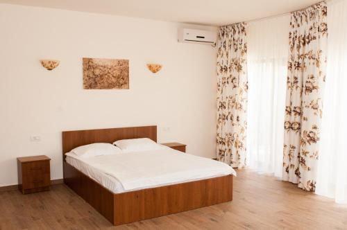 艾福雷诺德Complex Adal的一间卧室配有一张带白色床单和窗帘的床
