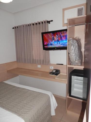卡坦杜瓦Hotel Lider - Catanduva的一间卧室,配有一张床和架子上的电视