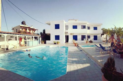 阿吉亚玛丽娜Helios Hotel的一群人在房子旁边的游泳池里
