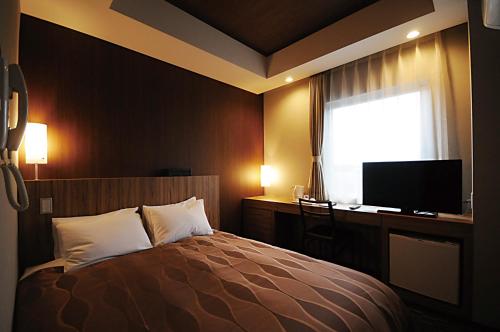 西之表市莱克斯通种子岛酒店的一间卧室配有一张床、一张书桌和一台电视