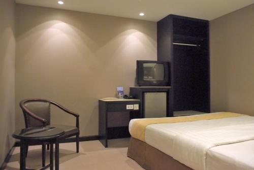 坤甸坤甸加亚马达酒店的一间卧室配有一张床、一台电视和一把椅子