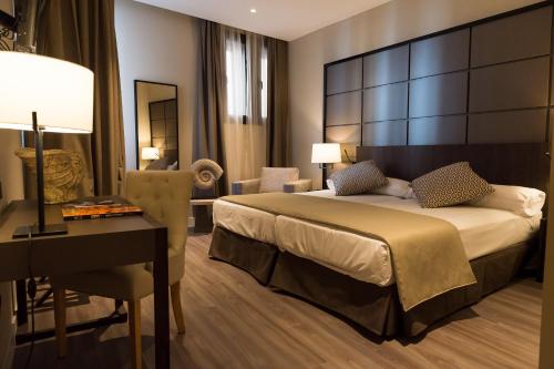 阿维拉瓦尔德拉巴内斯皇宫酒店的酒店客房配有一张床、一张书桌和一张书桌。