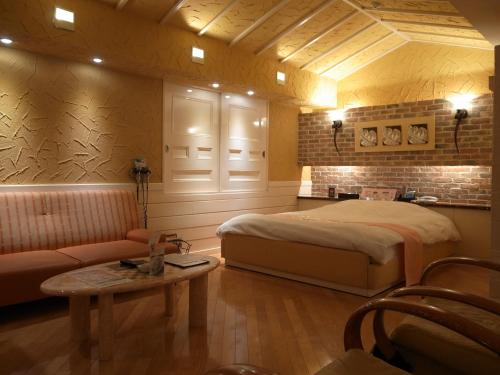 本庄市大酒店（仅限成人入住）的一间卧室配有一张床、一张沙发和一张桌子