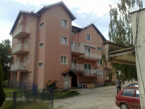索科矿泉村Apartments Petkovic的一座大型粉红色建筑,在街上设有阳台