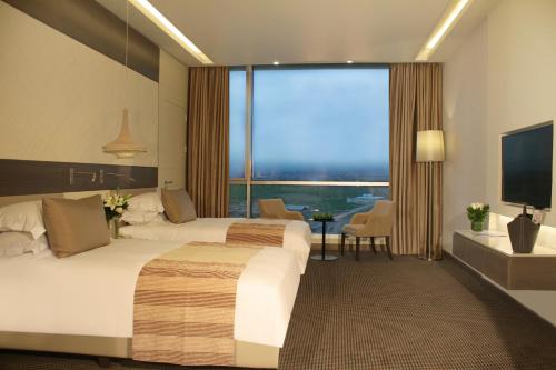 埃尔比勒Erbil Arjaan by Rotana的酒店客房设有两张床和大窗户。