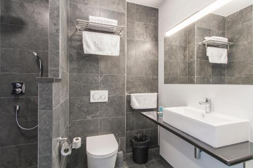 埃因霍温埃因霍温瓦勒巴斯蒂昂酒店的一间带水槽、卫生间和镜子的浴室