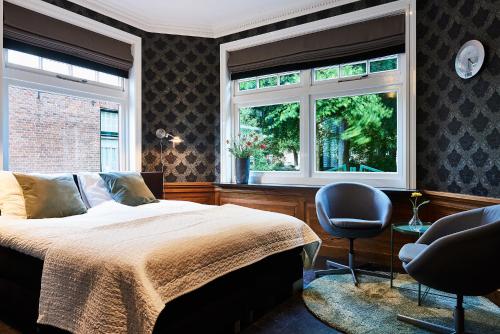 埃曼Guesthouse Villa Emmen的一间卧室设有床、两扇窗户和一把椅子