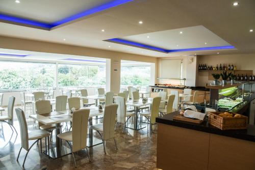 帕拉代西翁瓦里安乡村酒店的一间带桌子和白色椅子的餐厅以及一间厨房