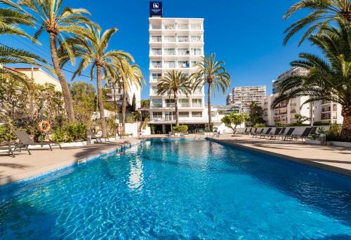 马略卡岛帕尔马玛丽温特欧洲之星酒店的一座棕榈树游泳池和一座高高的建筑