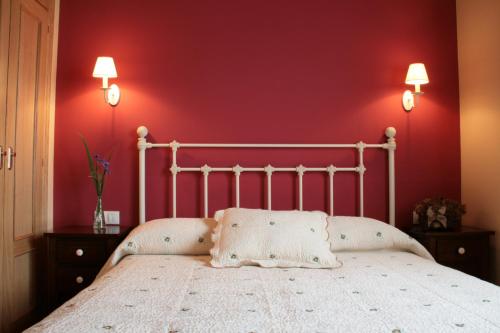 OviñanaApartamentos Rurales La Carbayala的卧室配有白色的床铺和红色的墙壁