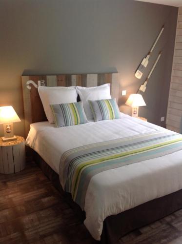 勒泰克Les Rives du Bassin的一间卧室配有一张带两盏灯的大型白色床。
