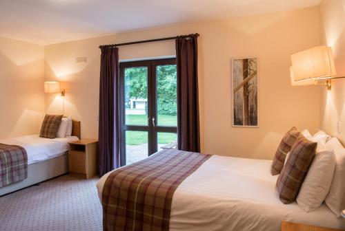 基拉尼Castlerosse Park Resort Holiday Homes的酒店客房设有两张床和窗户。